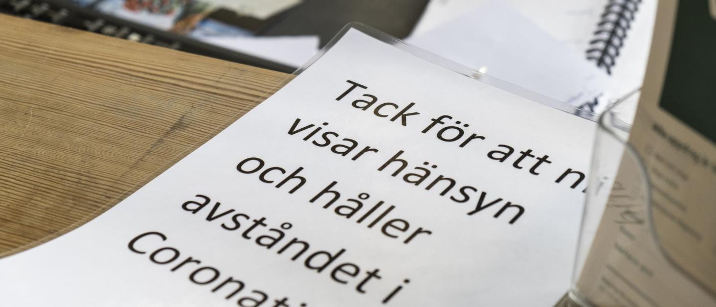 En lapp med texten Tack för att ni visar hänsyn och håller avståndet i Coronatid.