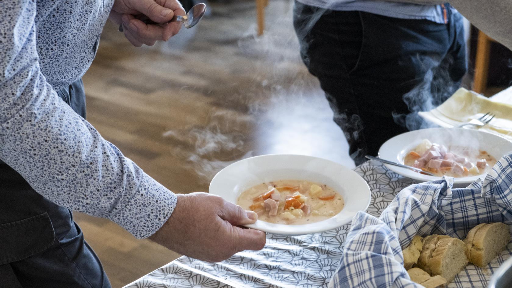 Någon håller en tallrik soppa i handen.