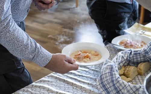 Någon håller en tallrik soppa i handen.