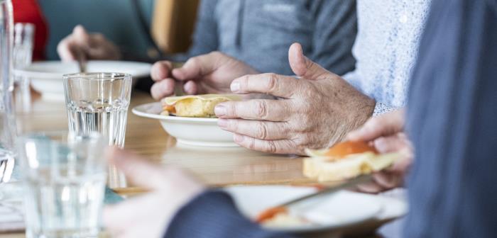 Några personer sitter runt matbordet och äter.