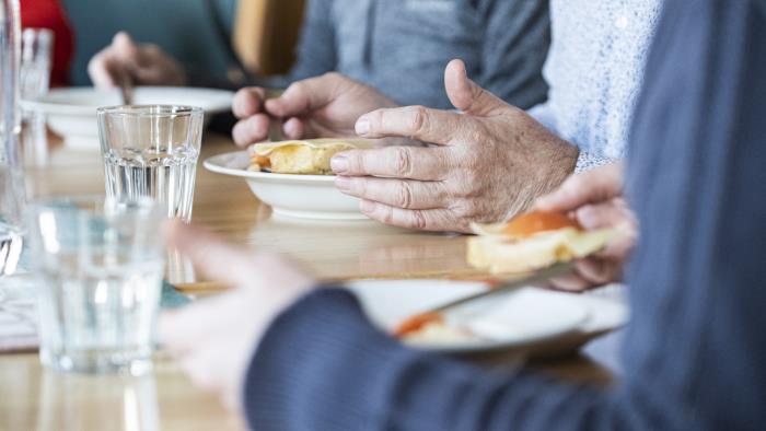 Några personer sitter runt matbordet och äter.