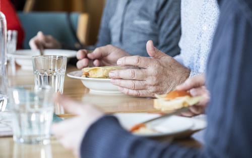 Några personer sitter runt matbordet och äter.