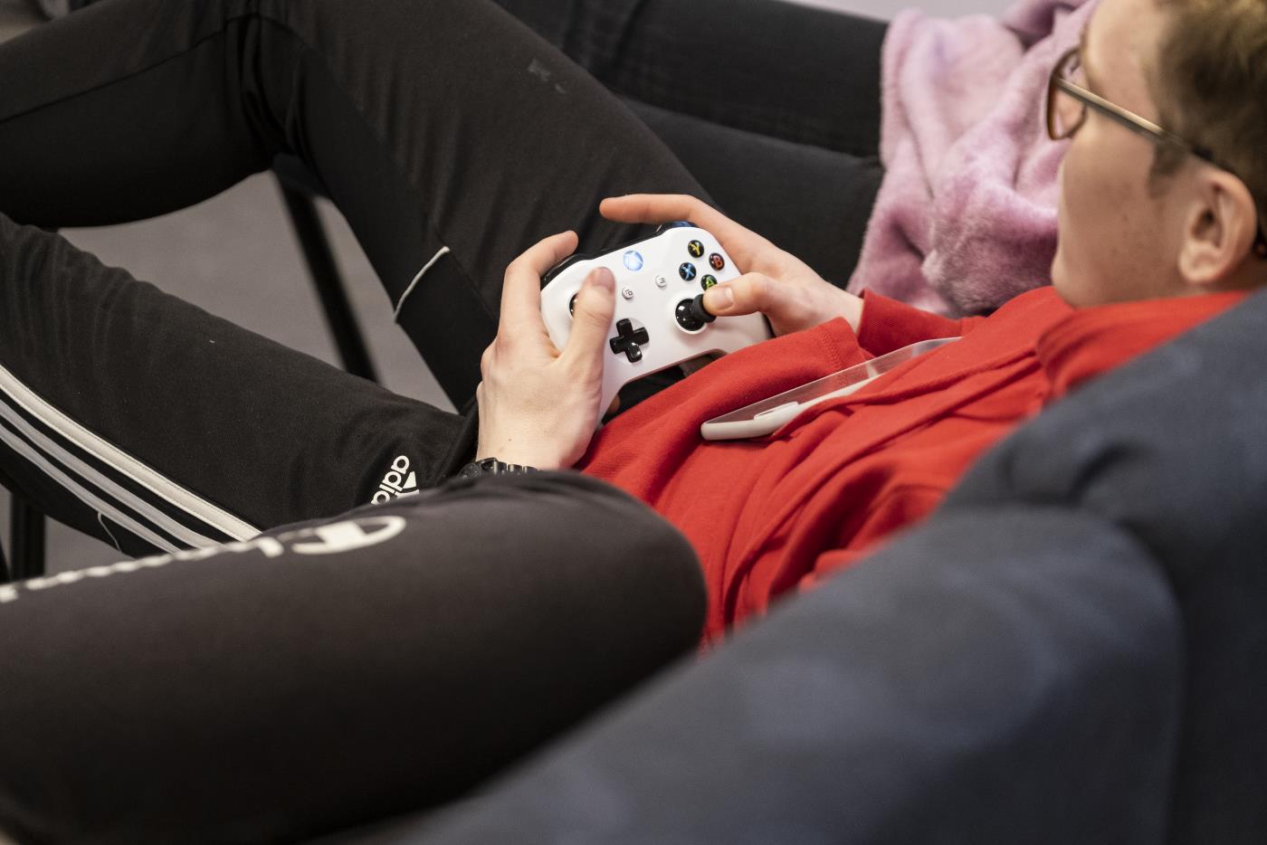 En ung kille sitter i en soffa och spelar tv-spel.