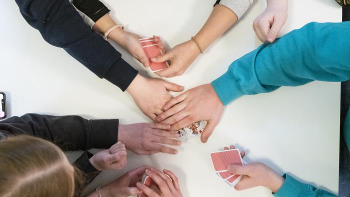 Några ungdomar spelar kort tillsammans.