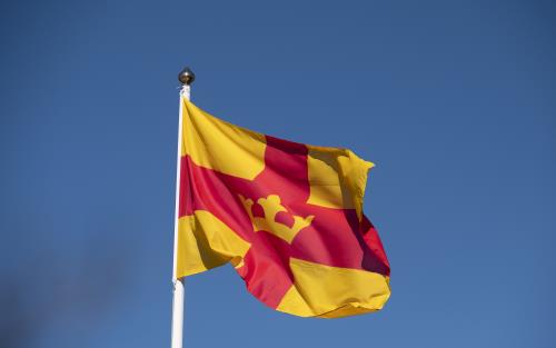 Svenska kyrkans flagga vajar mot en blå himmel.