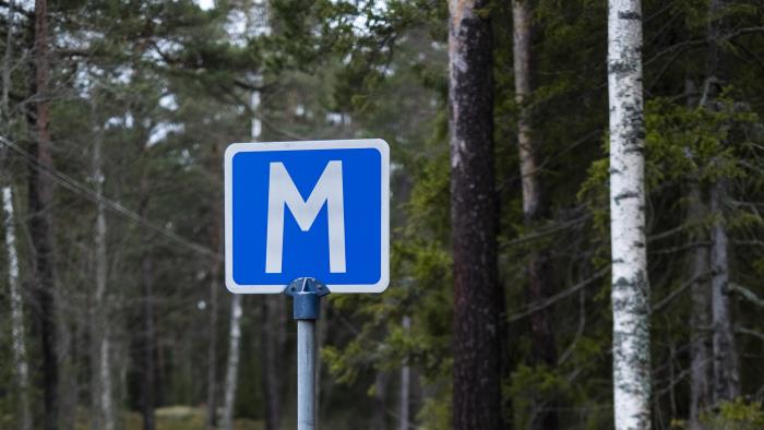 En skylt för mötesplats på en väg i skogen.