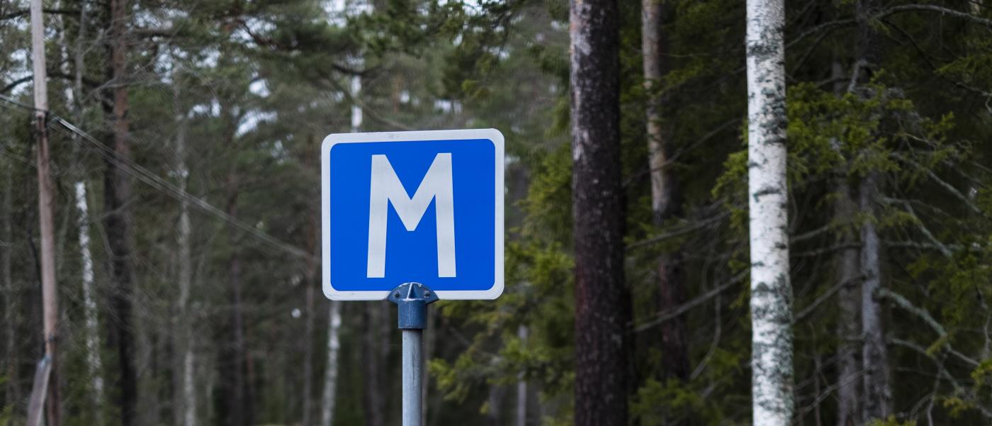 En skylt för mötesplats på en väg i skogen.