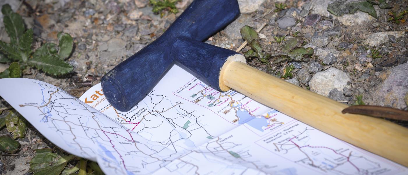 En vandringskäpp med blått handtag ligger på marken på en utvikt karta.