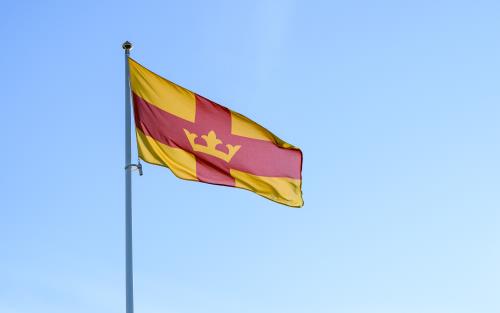 Svenska kyrkans flagga vajar mot en blå himmel.