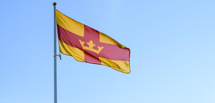 Svenska kyrkans flagga vajar mot en blå himmel.