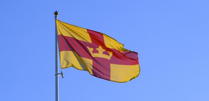 Svenska kyrkans flagga vajar mot en blå himmel.