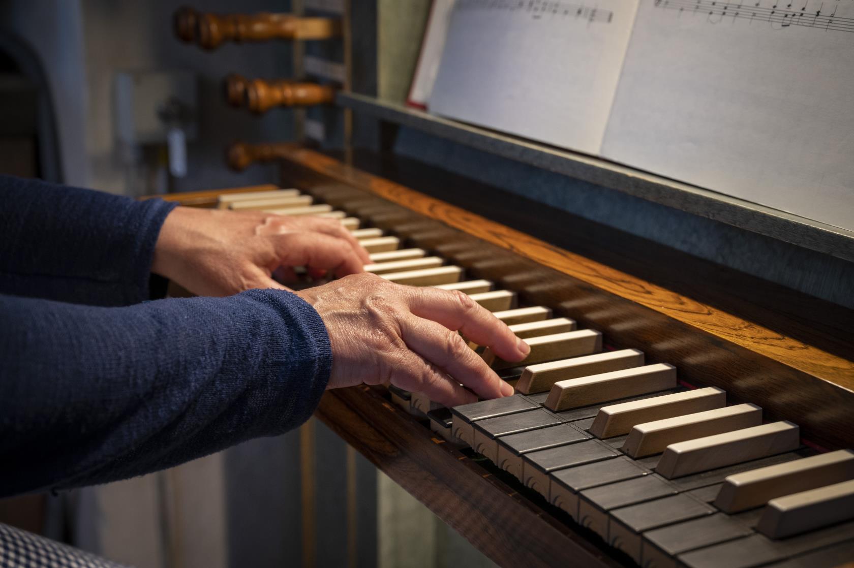 Ett par händer spelar på en kyrkorgel.