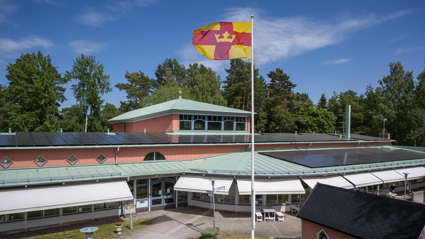 Magdalenakyrkan i Bålsta en solig dag. Svenska kyrkans flagga vajar utanför.