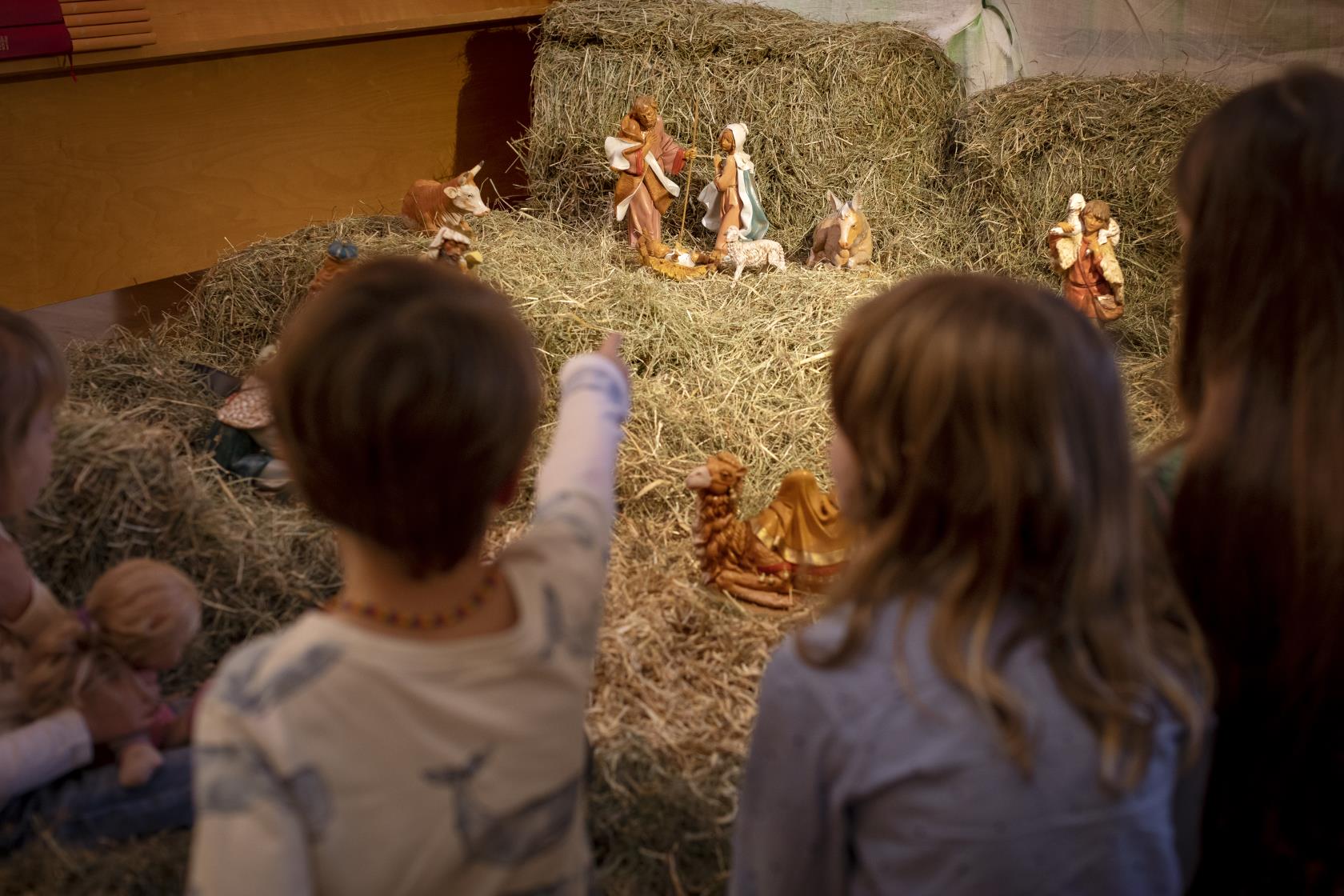 Två barn tittar på dockorna i julkrubban.