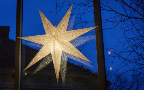 En vit adventsstjärna lyser upp ett fönster.