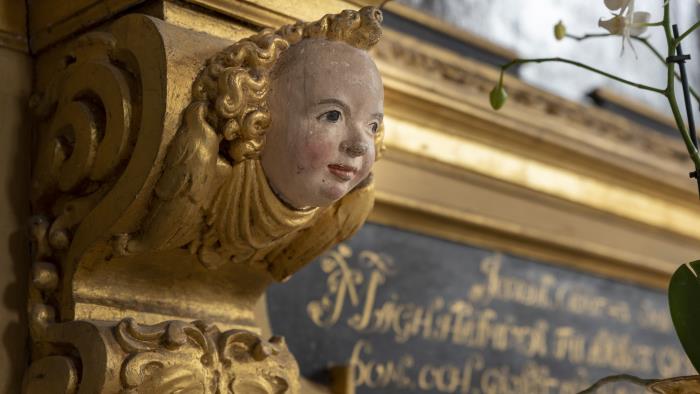 En ängels ansikte i ett guldmålat träornament.