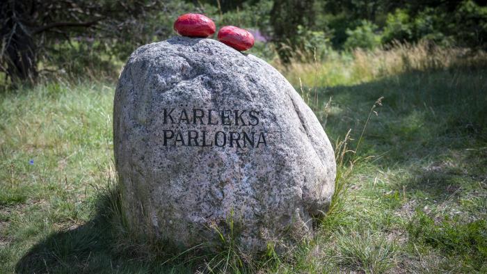 Två mindre röda stenar ligger ovanpå en större med texten Kärlekspärlorna.