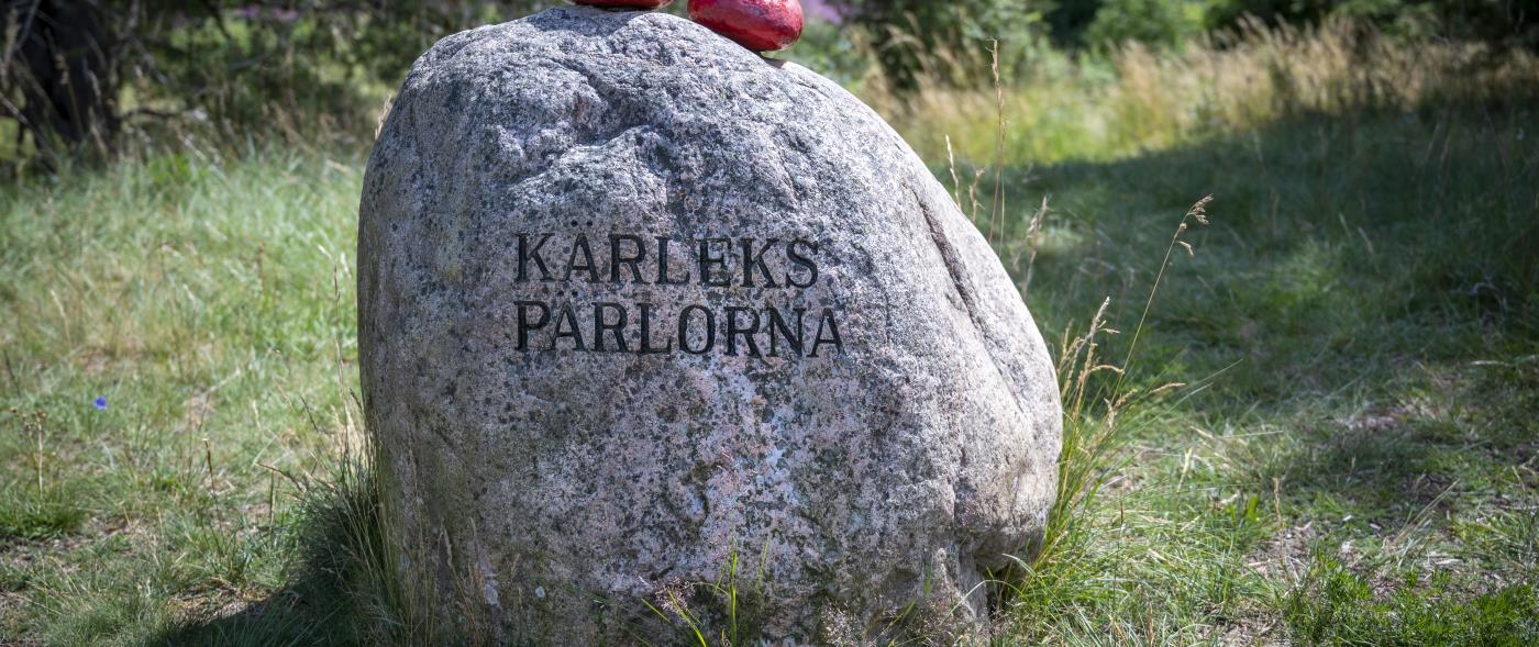 Två mindre röda stenar ligger ovanpå en större med texten Kärlekspärlorna.