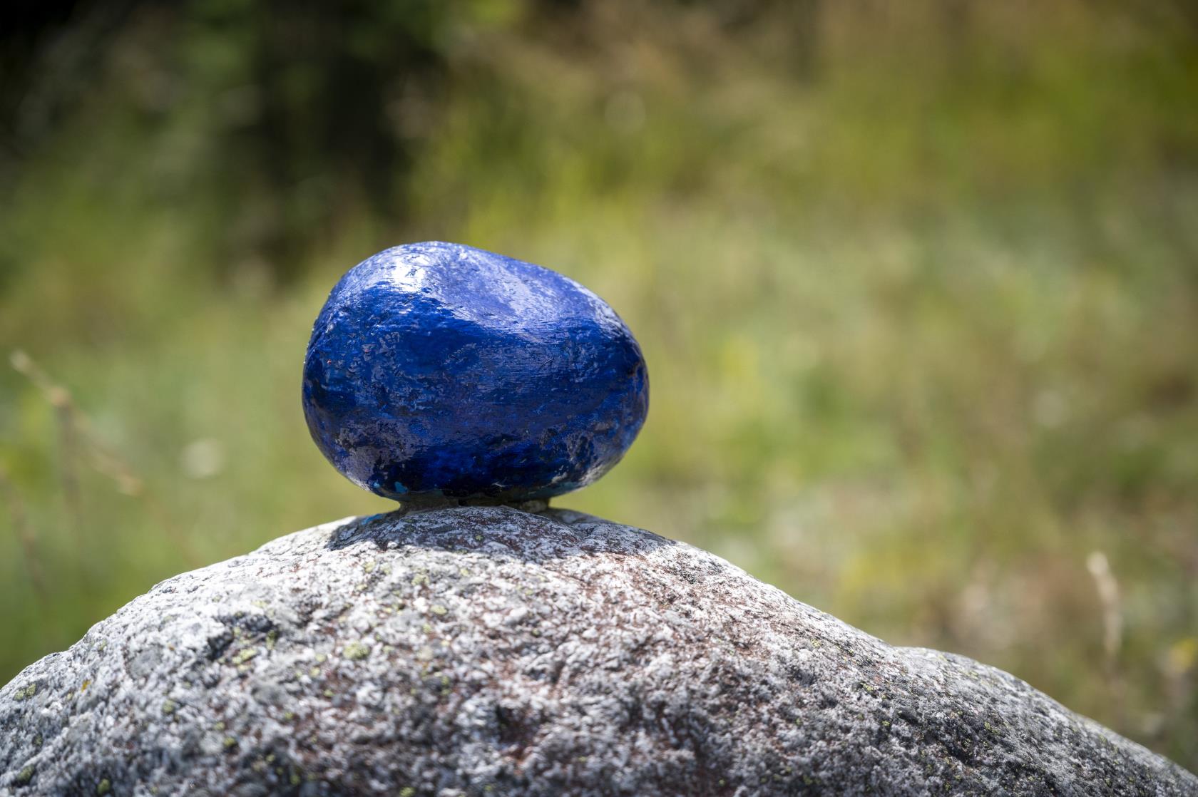 En mindre blåmålad sten ligger ovanpå en större.