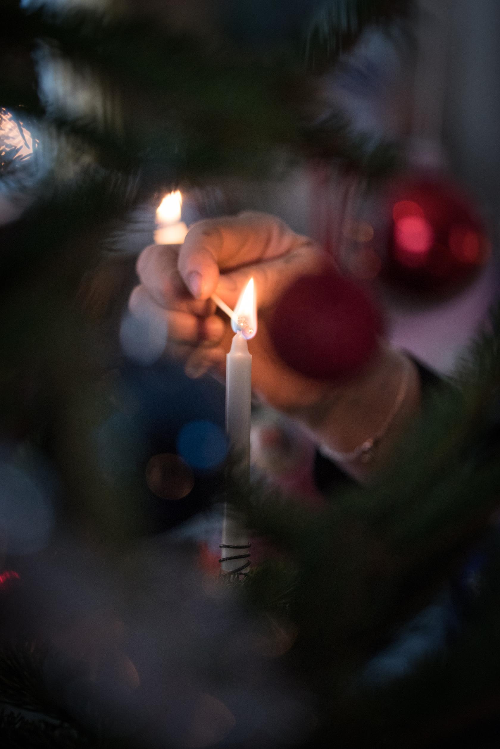 Någon tänder ett ljus i julgranen.