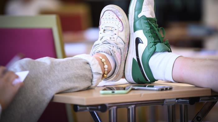 Två ungdomar jämför sina skostorlekar på ett bord.