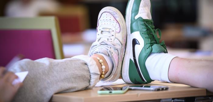Två ungdomar jämför sina skostorlekar på ett bord.