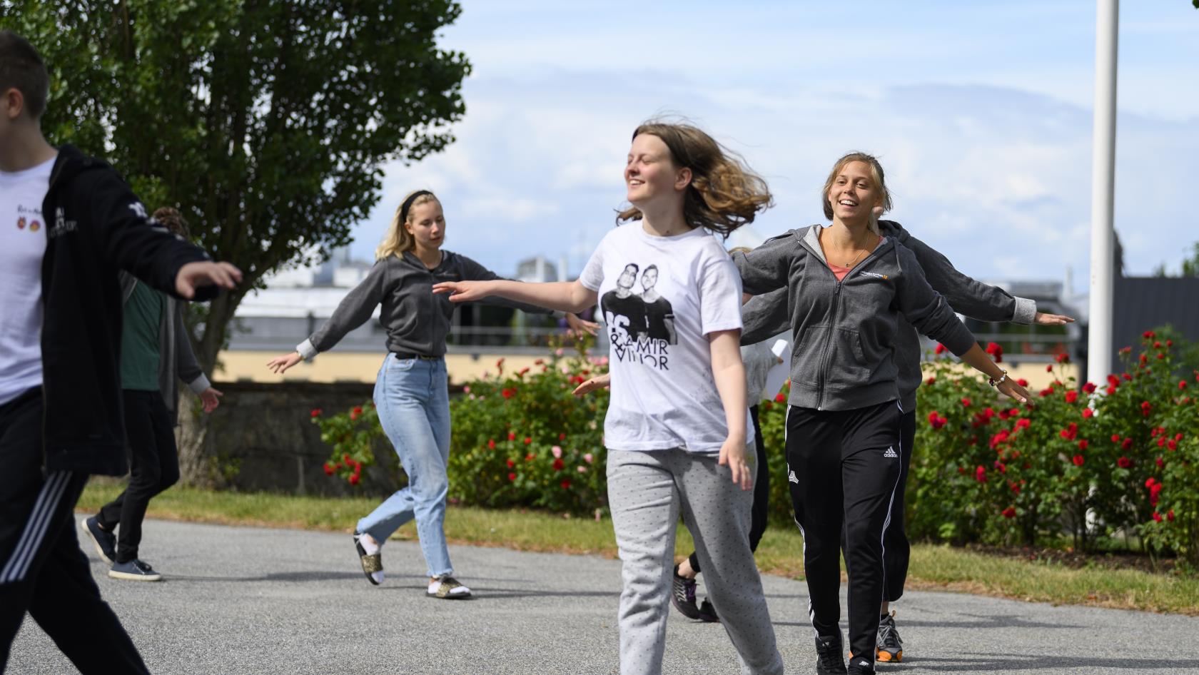 Några glada ungdomar går runt i en ring utomhus.