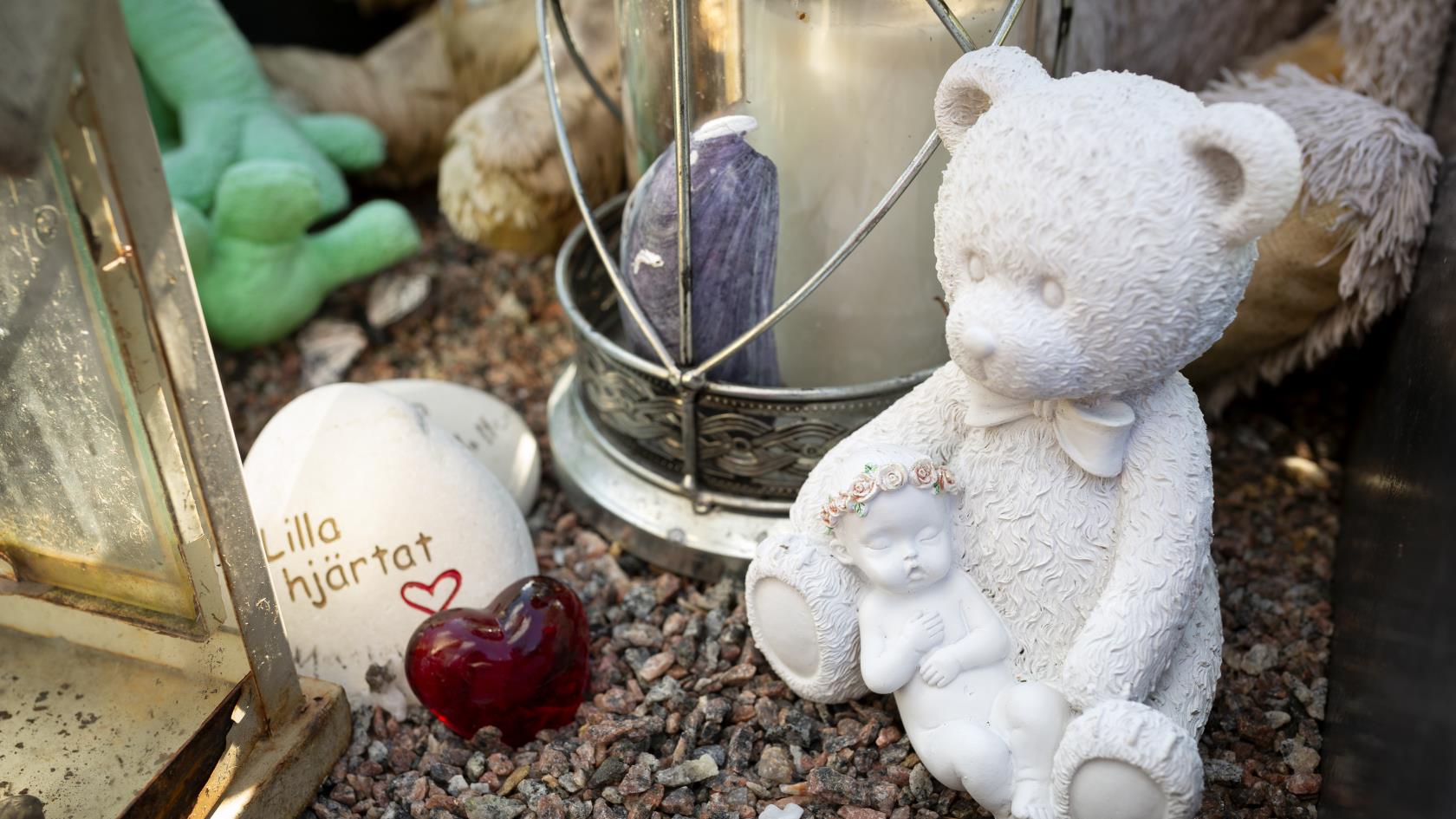 En grav dekorerad med bland annat en nallebjörn, ett hjärta i glas och en sten med texten Lilla hjärtat.