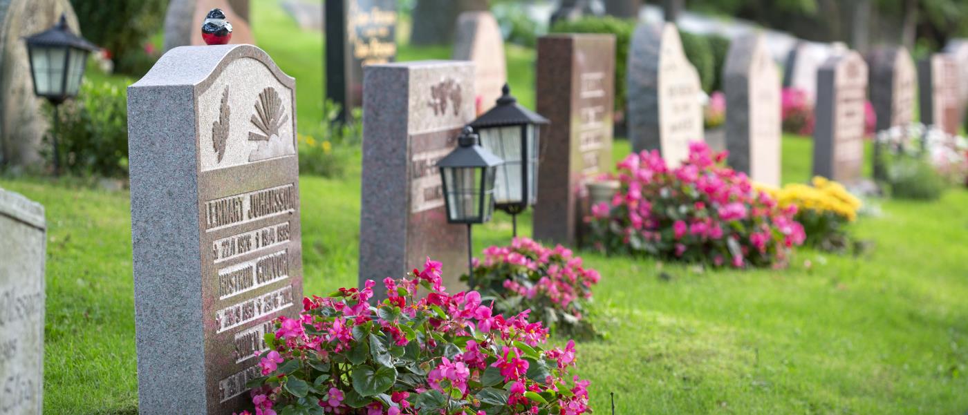 Gravar dekorerade med färggranna blommor på en kyrkogård.