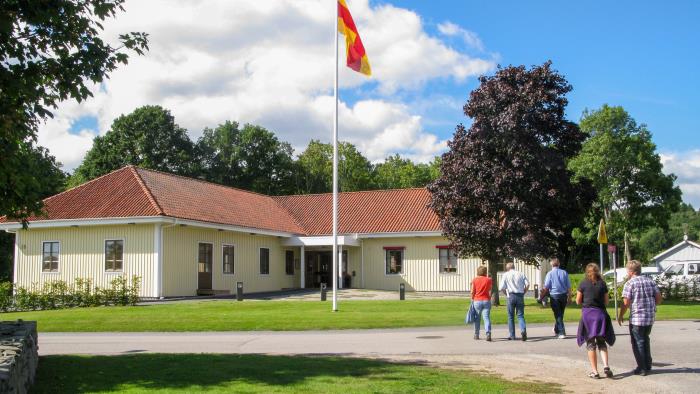 Några människor är på väg mot ett församlingshem med Svenska kyrkans flagga hissad.