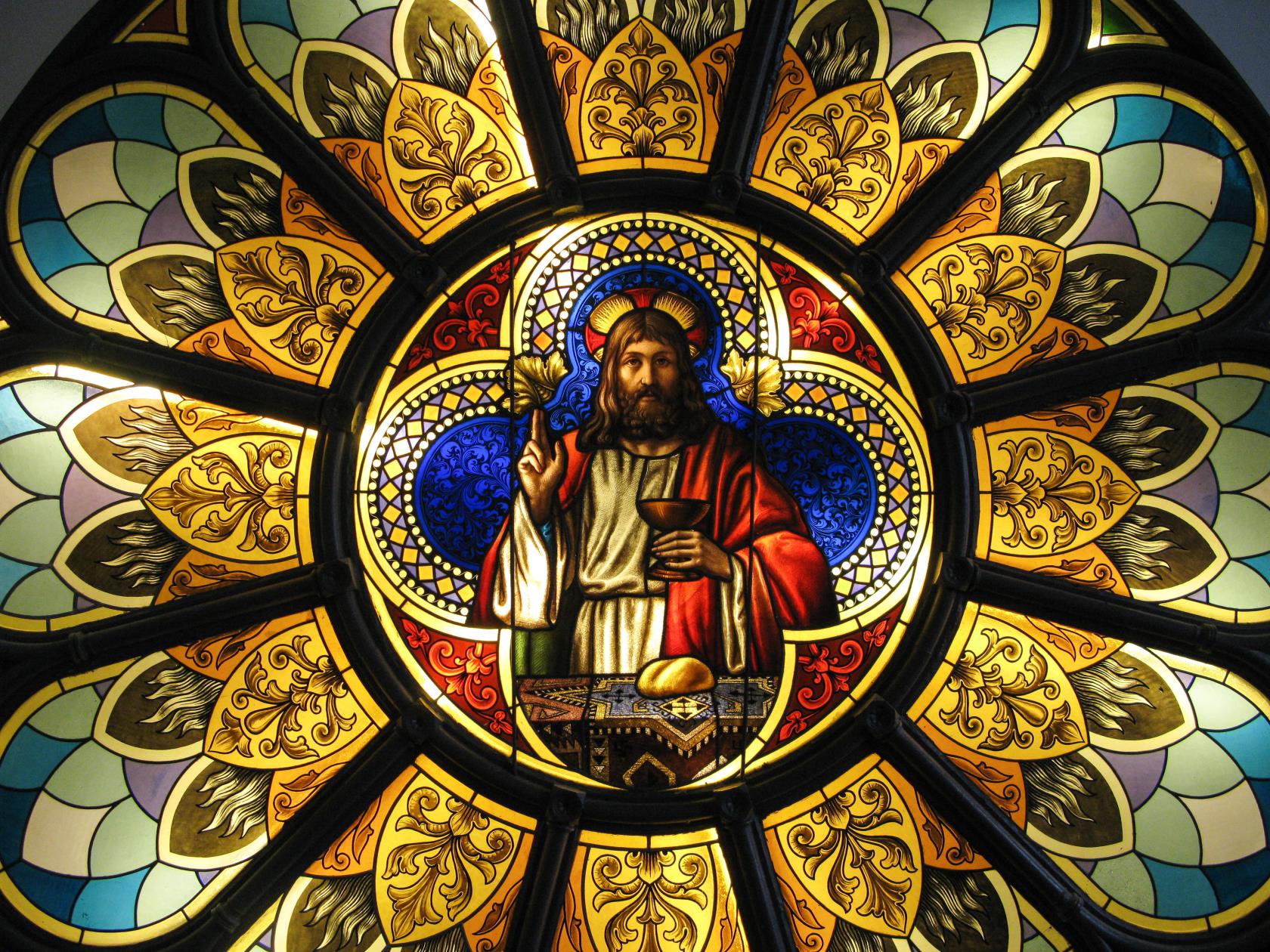 Ett runt kyrkfönster. I mitten syns Jesus som delar ut nattvard.