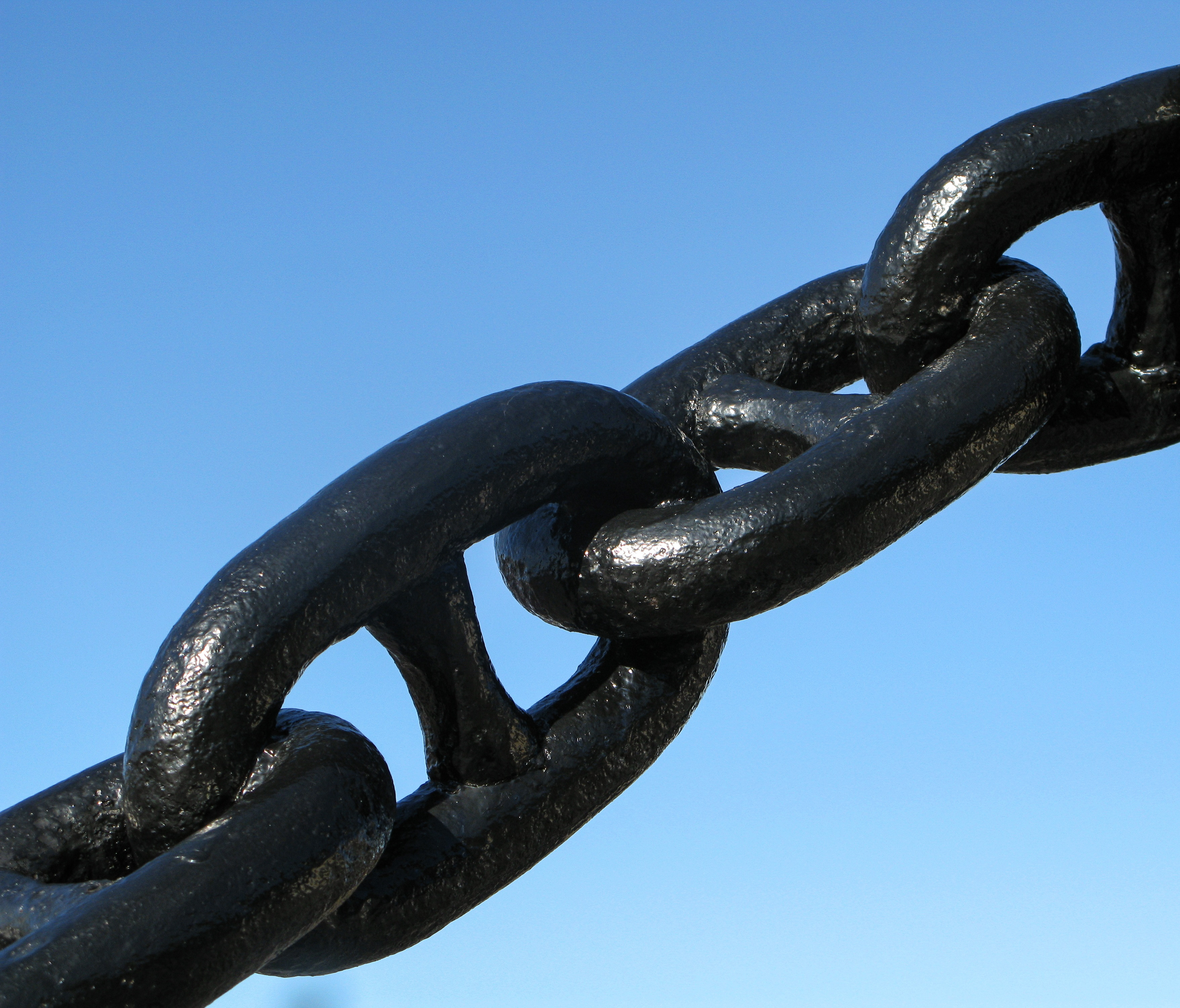 Tjocka svarta kedjelänkar mot en blå himmel.