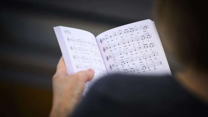 En person håller i en uppslagen psalmbok.