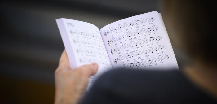 En person håller i en uppslagen psalmbok.