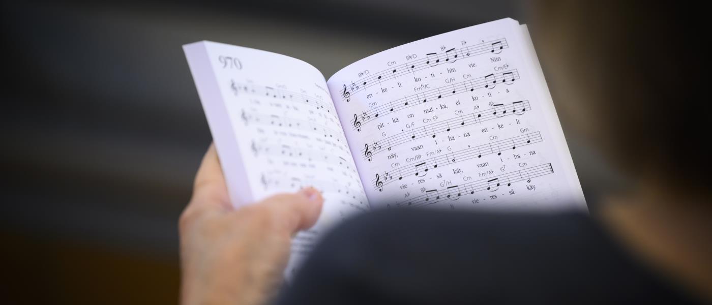En person håller i en uppslagen psalmbok.