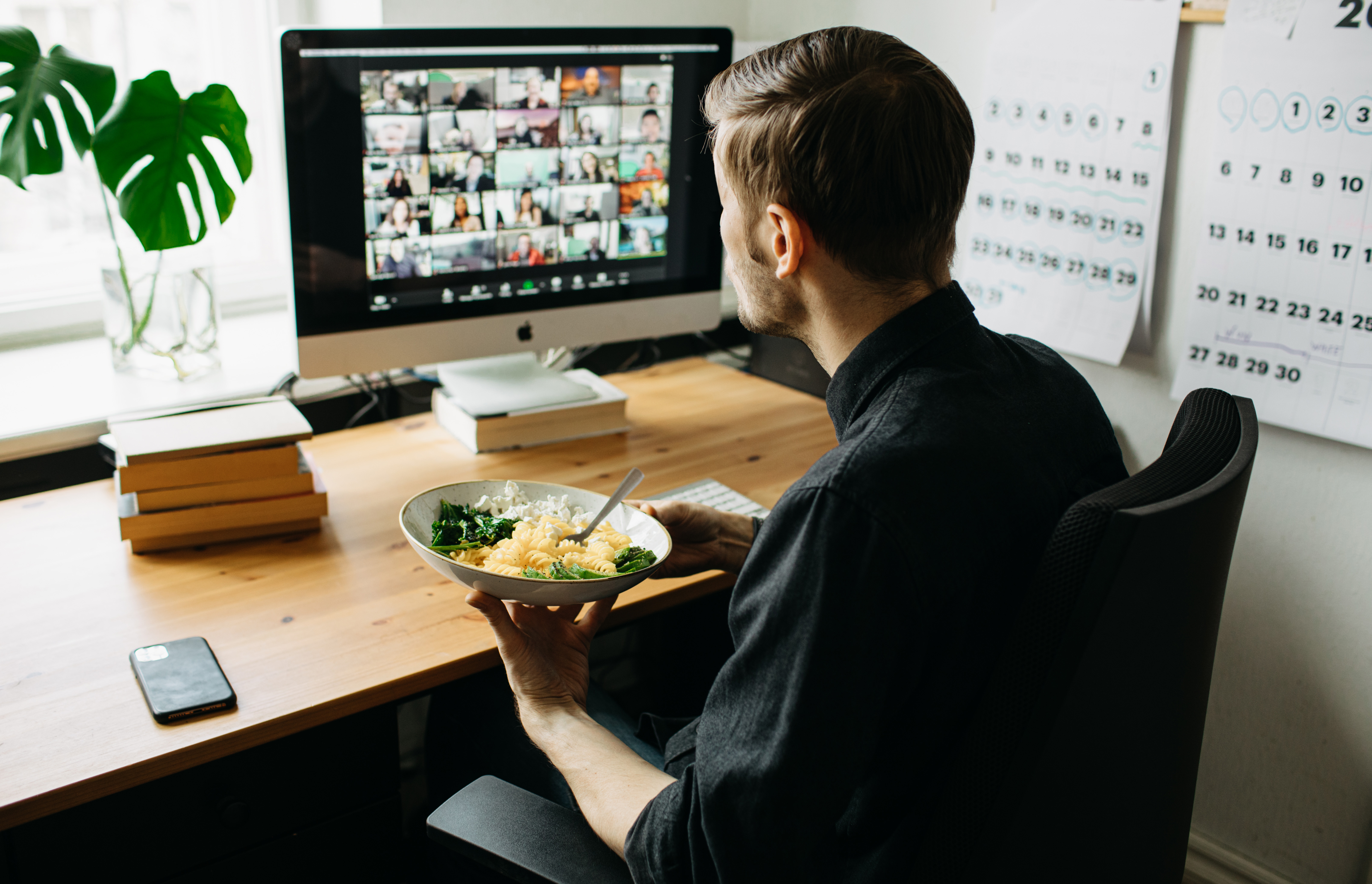 En man äter lunch vid datorn medan han deltar i ett video-möte.