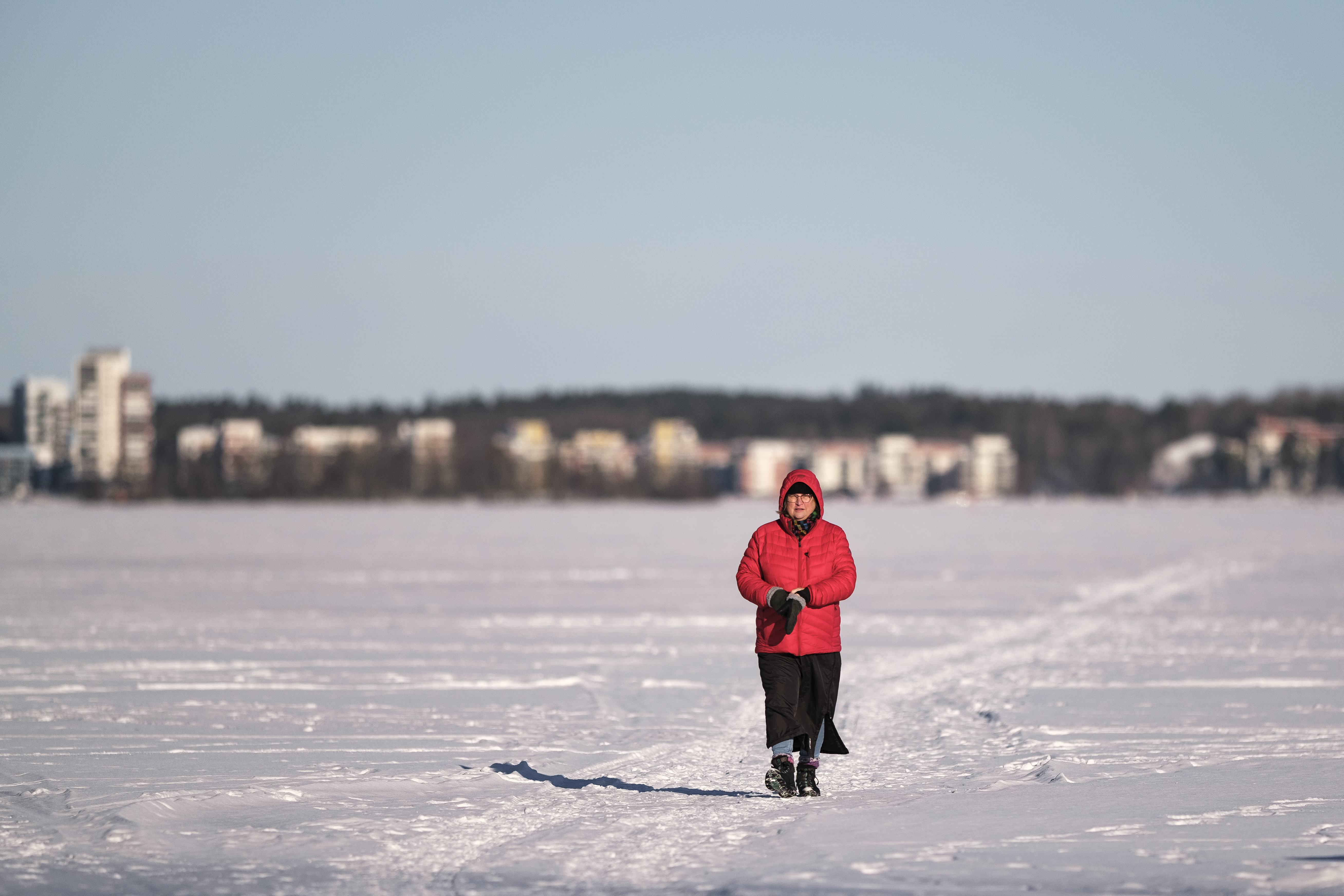 En kvinna är ute på långpromenad. Det är vinter och solen skiner.