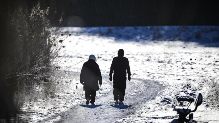 Två personer är ute på långpromenad. Det är vinter och solen skiner.