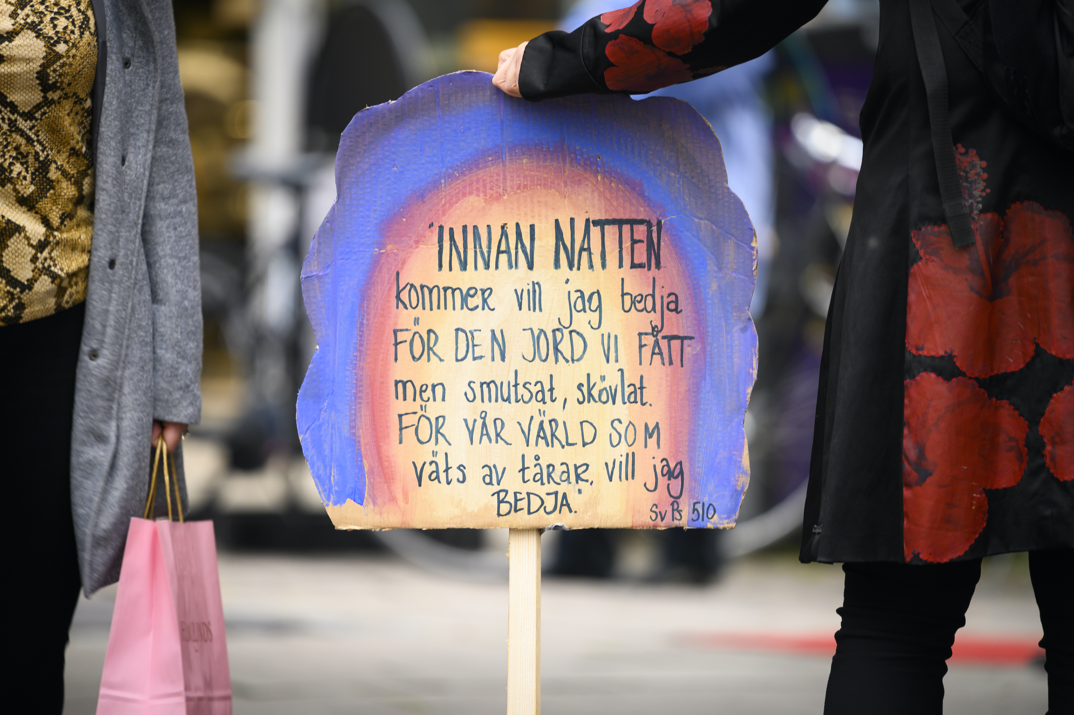 En demonstrant håller i ett färggrant plakat.