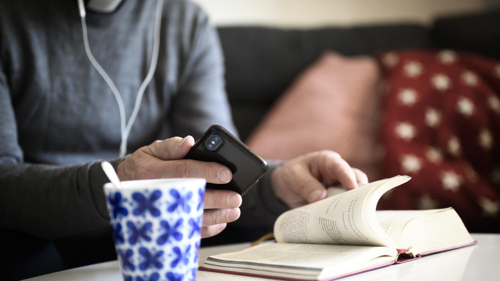 Jourhavande präst pratar i mobiltelefon med bibeln uppslagen framför sig.