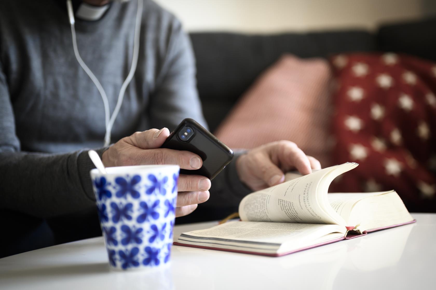Jourhavande präst pratar i mobiltelefon med bibeln uppslagen framför sig.