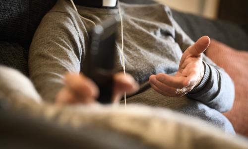 En präst sitter med hörlurar och pratar i mobiltelefon.