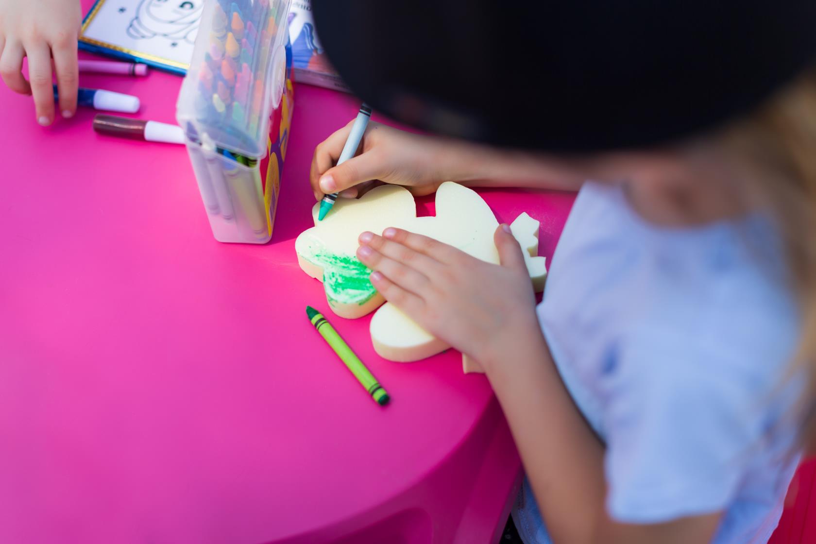 Ett barn målar med en grön krita på en modell i form av en groda.