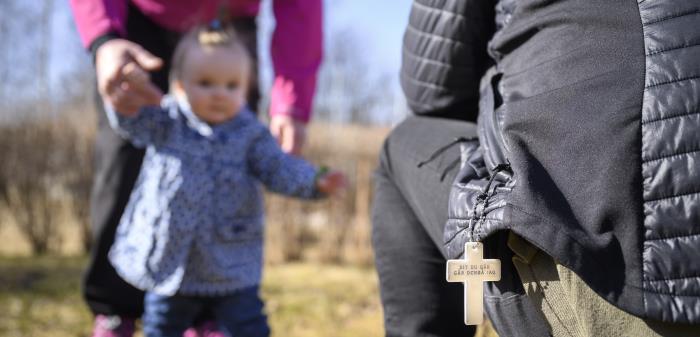 En bebis på vårpromenad får hjälp att lära sig gå av sina föräldrar.