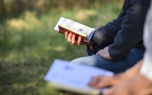 Två personer sitter bredvid varandra utomhus med varsin psalmbok.