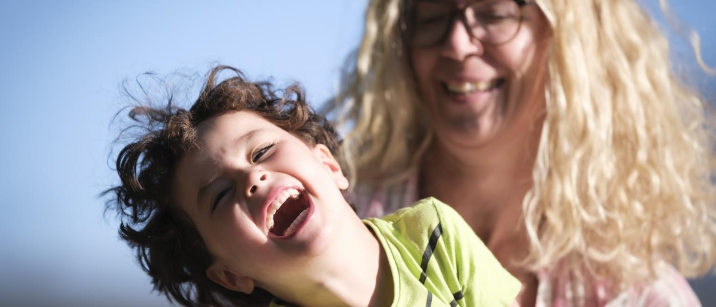 Ett barn gapskrattar i sin mammas knä.