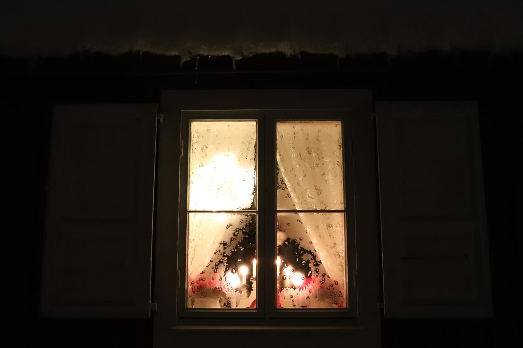 En adventsljusstake lyser upp ett fönster.