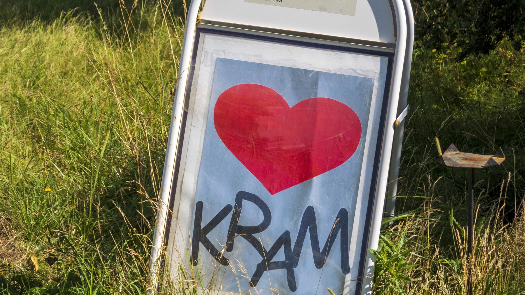 En skylt med ett hjärta och texten Kram står vid en landsväg i gräset.