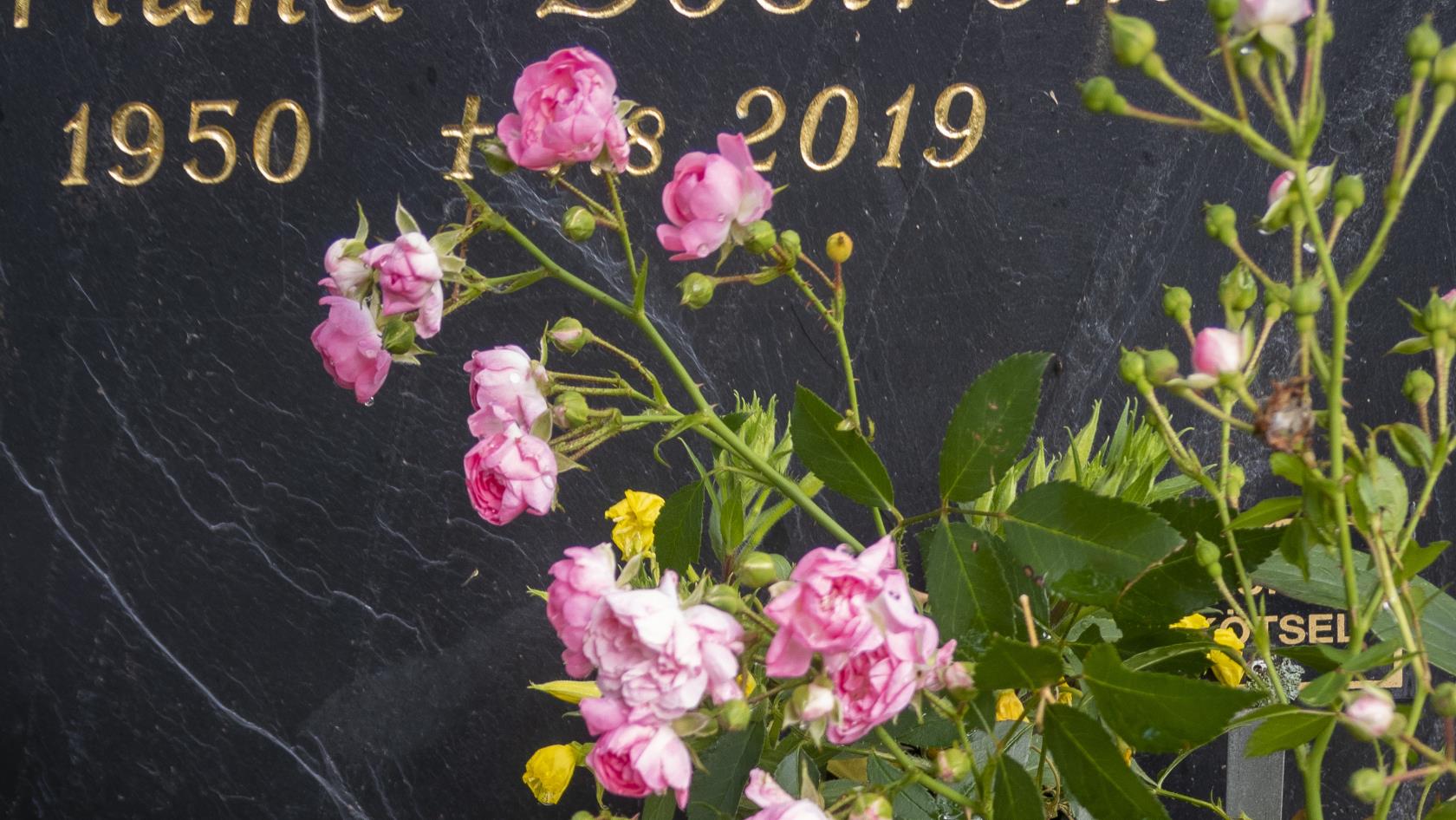 Blommor och ett ljusblått hjärta vid en gravsten.