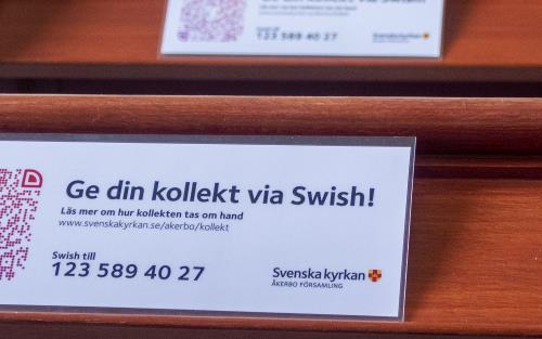 Lappar med texten Ge din kollekt via Swish ligger i kyrkbänkarna.